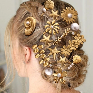 Golden 18k seashell and pearl hair clip set styled on an elegant braided hairstyle