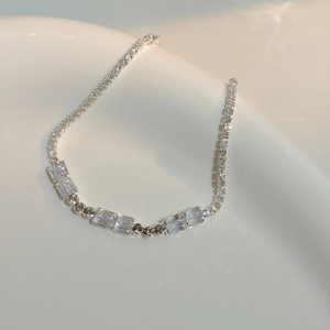 Macro shot of sparkling silver zirconia stones on a bracelet inside a white ceramic bowl