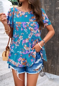 Vue lifestyle d'un haut à manches courtes en mousseline fleurie bleue avec un short en jean