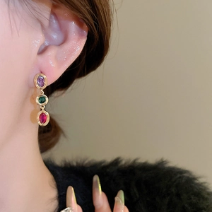 Close-up of triple oval zircon drop earrings featuring purple, green, and pink stones