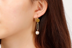 Close-up of elegant gold pearl drop earrings worn by a model in a minimalist style