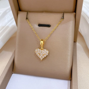 Makroansicht der goldenen Herzkette mit glitzernden Kristallen in einer Geschenkbox