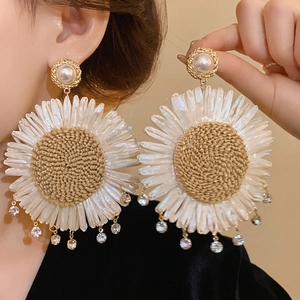 Detail of vintage sunflower earrings with woven texture, pearls, and rhinestone tassels