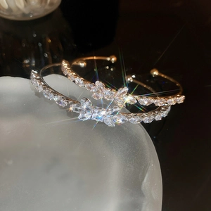 Elegant gold bow-shaped open bangle with sparkling cubic zirconia floral design