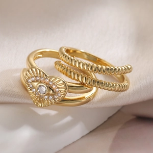Golden double-layer evil eye ring with heart-shaped zircon on beige silk background
