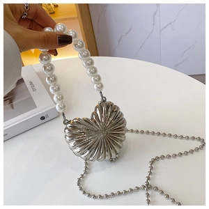 Detail of silver heart-shaped metal evening bag with pearl handle and ball chain
