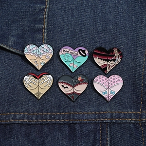 Close-up of six creative heart-shaped enamel pins on denim, featuring bad witch and skull hand