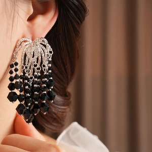 Close-up of model wearing silver tassel earrings with tiered black faceted glass beads