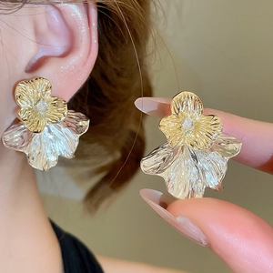 Detailansicht zweifarbiger Metall-Blumenohrringe mit kleinen klaren Steinen am Modell