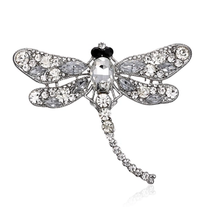 Macro detail of silver dragonfly brooch with sparkling rhinestones and black gem eyes