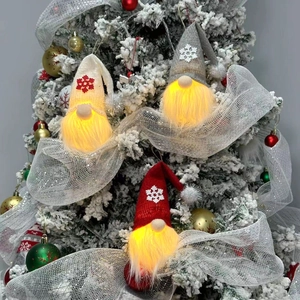Three glowing Christmas gnome plush ornaments in beige, grey, and red hanging on a festive tree