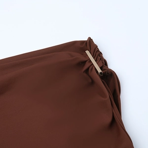Détail d'une robe marron à épaules dénudées avec une boucle décorative en métal doré