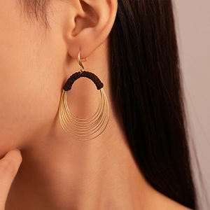 Close-up of golden multi-layer circle earrings with black fabric wrap on a female model