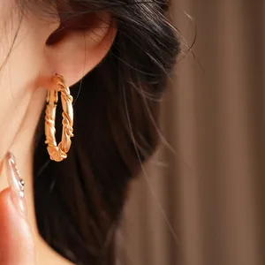 Elegant gold twisted hoop earring with spiral texture worn by a model in warm lighting
