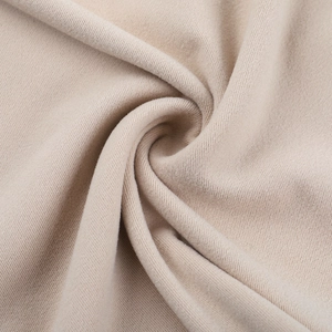 Close-up of soft beige knitted cotton fabric texture with flexible spiral fold detail