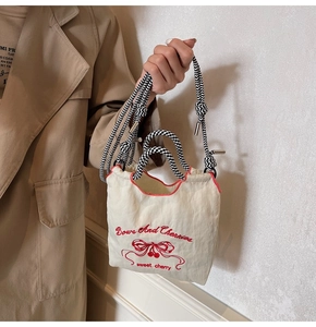 Detail of embroidered Bows And Cherries nylon bag with checkered rope handle