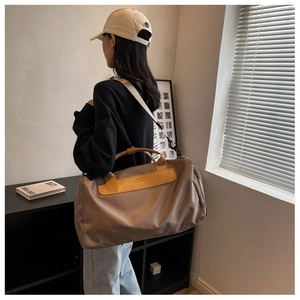 Rear view of a khaki gym bag with leather handles shown in a lifestyle indoor setting