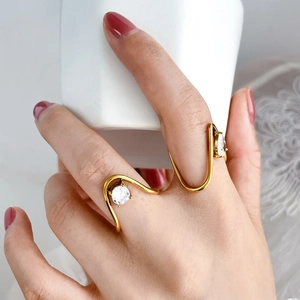 Close-up of golden minimalist U-shaped rings with round zircon stones on a model