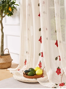 Detail of sheer beige curtain with festive red floral embroidery and delicate mesh texture