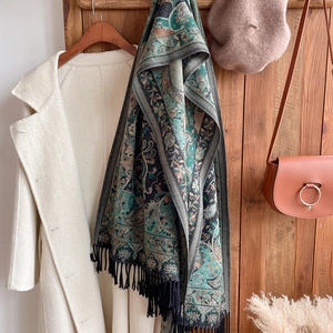 Detail showing vintage paisley pattern scarf with black tassels on a beige coat