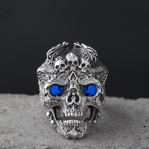 Macro detail of gothic skull ring with blue crystal eyes on a textured stone base