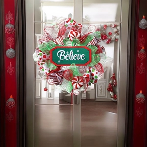 Close-up of mesh Christmas wreath with 'Believe' sign on a glass door background