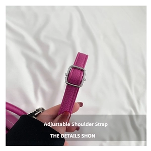 Détail de la bandoulière réglable sur le sac fuchsia en cuir PU avec motif litchi