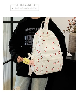 Rear view of a model wearing a white corduroy backpack with red cherry print and beige straps