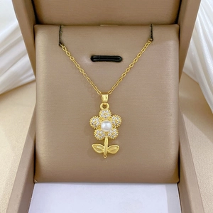 Detail of gold flower pendant necklace with diamonds and pearl on brown velvet