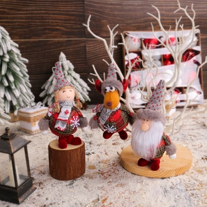 Standing Santa reindeer and gnome doll ornaments in red-grey plaid fabric on winter snow
