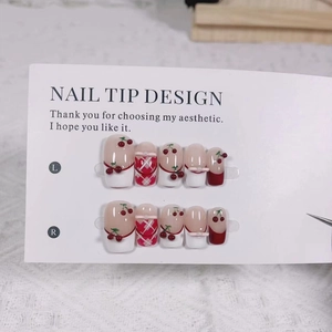 Detail view of handmade press-on nails with 3D cherry patterns and red gingham design