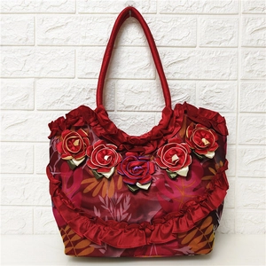 Detail of red floral tote bag featuring 3D ribbon roses and ruffled mesh accents