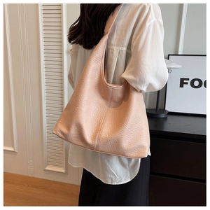Detail of soft pink tote bag featuring a lychee leather texture and wide shoulder strap