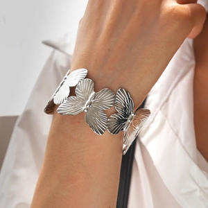 Detailed close-up of a silver butterfly-patterned open bangle worn on a wrist