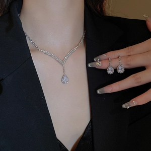 Close-up of V-shaped silver necklace and teardrop crystal earrings on a model