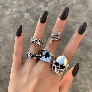 Gothic silver rings featuring skull and snake patterns on hand with black nails