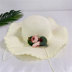 Détail d'un chapeau de paille crème avec bord ondulé et décoration florale de rose