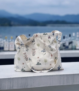 Detail of floral canvas tote bag on stone surface with a scenic lake and mountain background