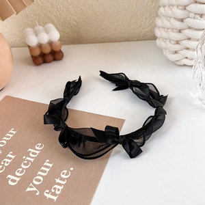 Detail of elegant black mesh lace headband with multiple bows on a minimalist background