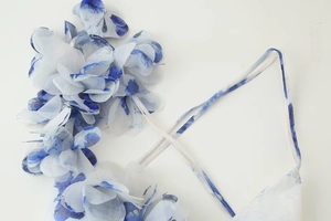 Détail de fleurs en mousseline 3D et imprimé floral bleu sur robe d'été blanche