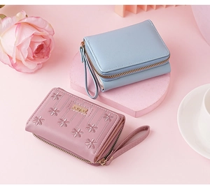 Close-up of small faux leather wallet with floral embroidery and wrist strap details