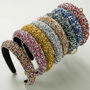 Sparkling padded rhinestone headbands in multiple colors on a sleek metal display stand