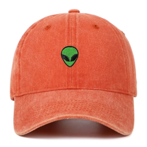 Dettaglio del ricamo alieno verde su un cappellino in cotone lavato color corallo