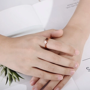 Détail d'une bague amovible 2-en-1 avec fleurs noires et blanches sur anneau rose doré