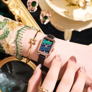 Detail of vintage square emerald dial watch with gold case and black leather strap