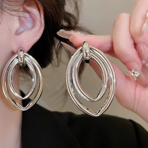 Détail de boucles d'oreilles pendantes ovales triples en argent au fini métallique épuré