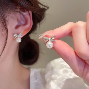 Gros plan sur des boucles d'oreilles nœud avec cristaux brillants et perles blanches