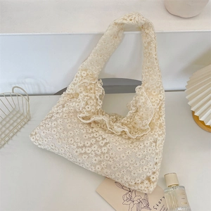 Detailed embroidery of daisy lace patterns and ruffle trim on this off-white shoulder bag