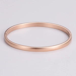 Detail of rose gold metal bracelet showing the snap buckle and brushed texture finish