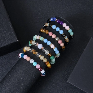 Detail of colorful natural stone beaded bracelets including tiger eye and amethyst on a black stand